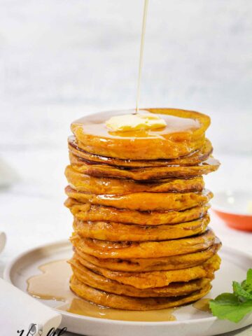 Fluffy pumpkin pancakes topped with butter and maple syrup.