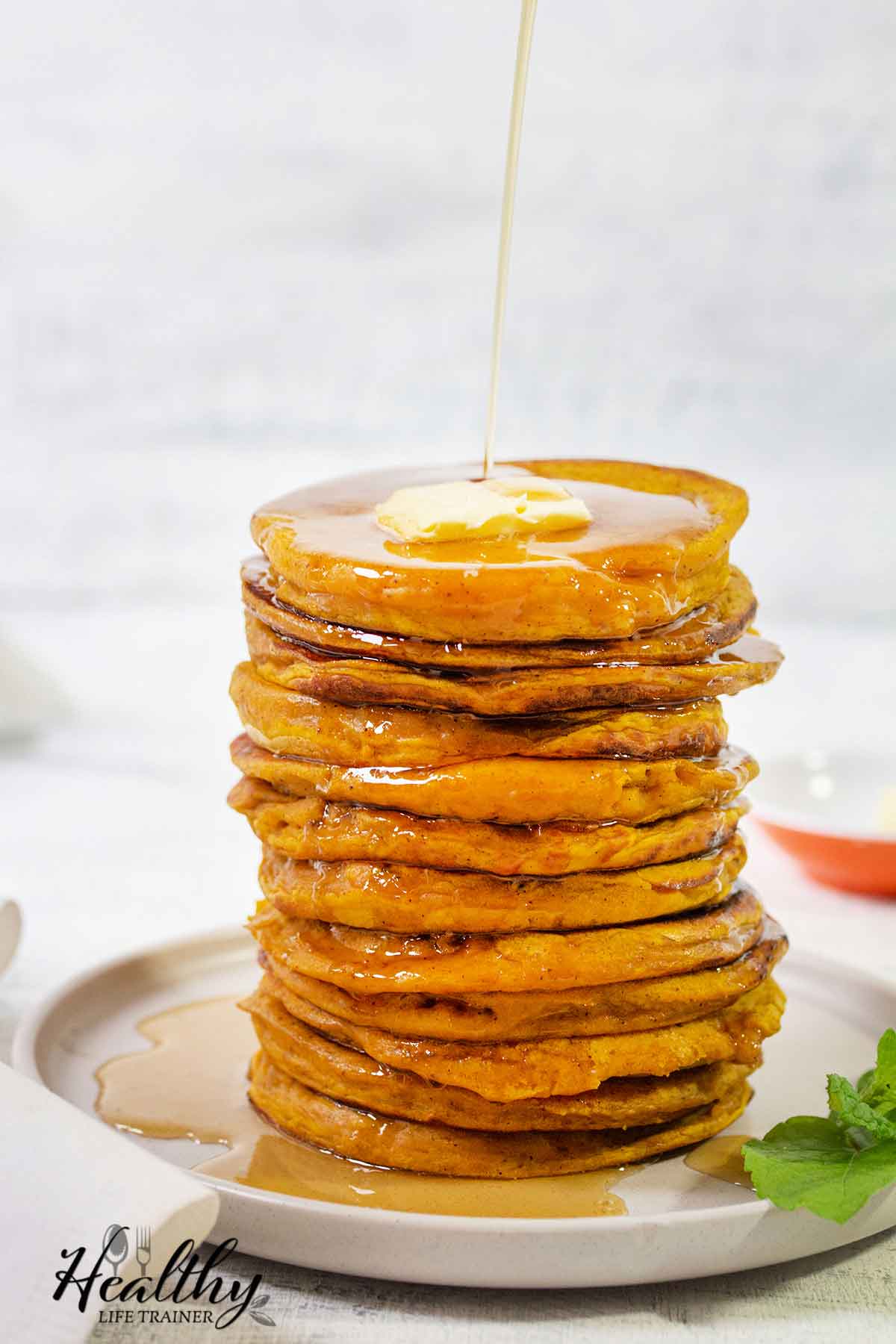 Fluffy pumpkin pancakes topped with butter and maple syrup.