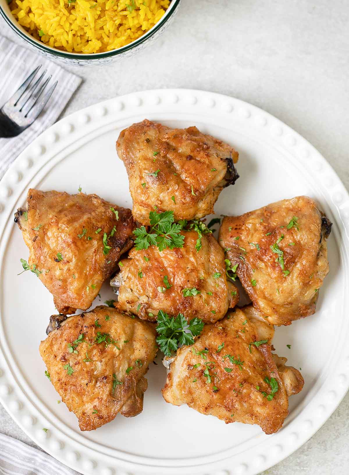 Bon in and skin on baked chicken thighs in a plate.