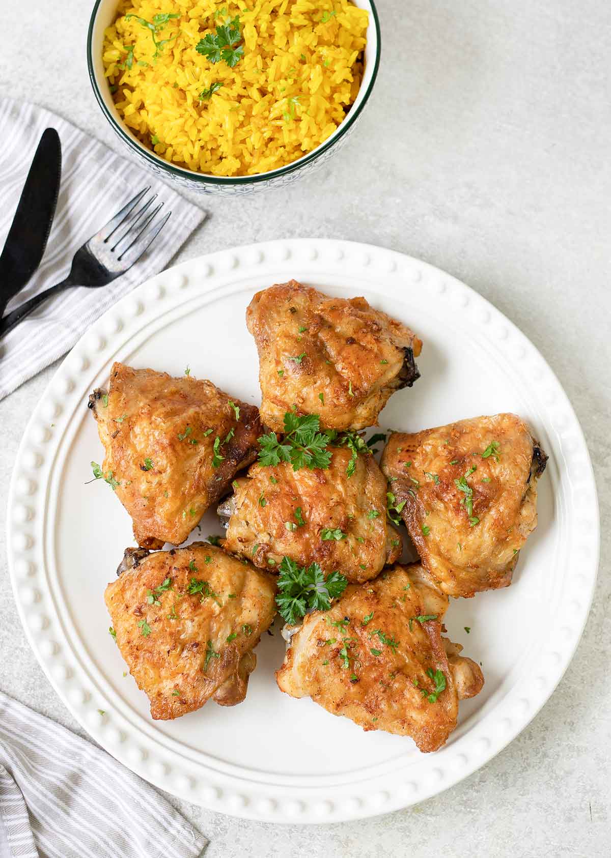 Bon in and skin on baked chicken thighs in a plate.