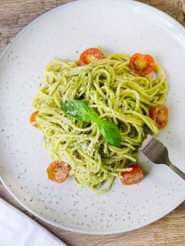 Creamy avocado sauce pasta in a plate along with some cherry tomatoes.