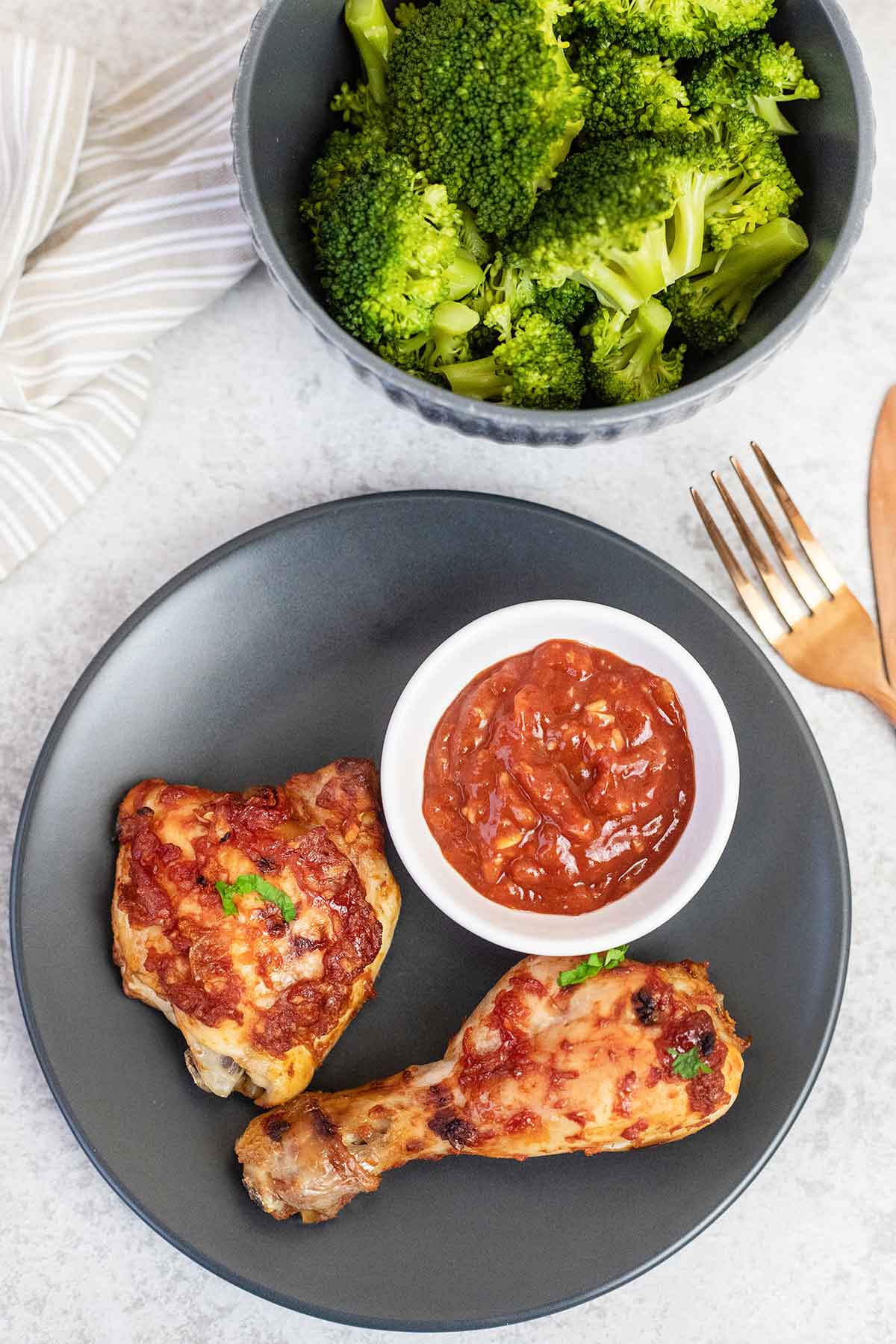 Baked bbq chicken legs & thighs and a bowl of bbq sauce.