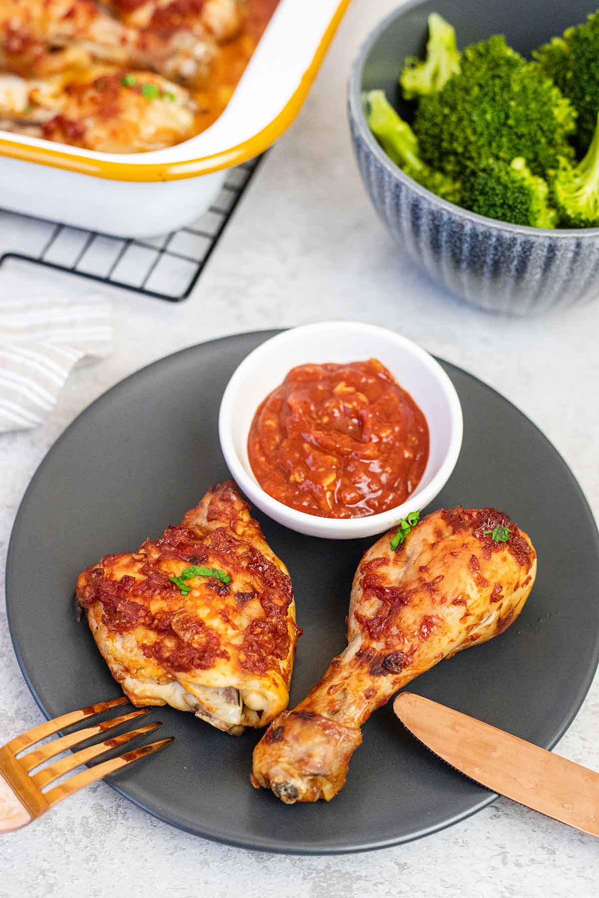 Baked bbq chicken legs & thighs and a bowl of bbq sauce.