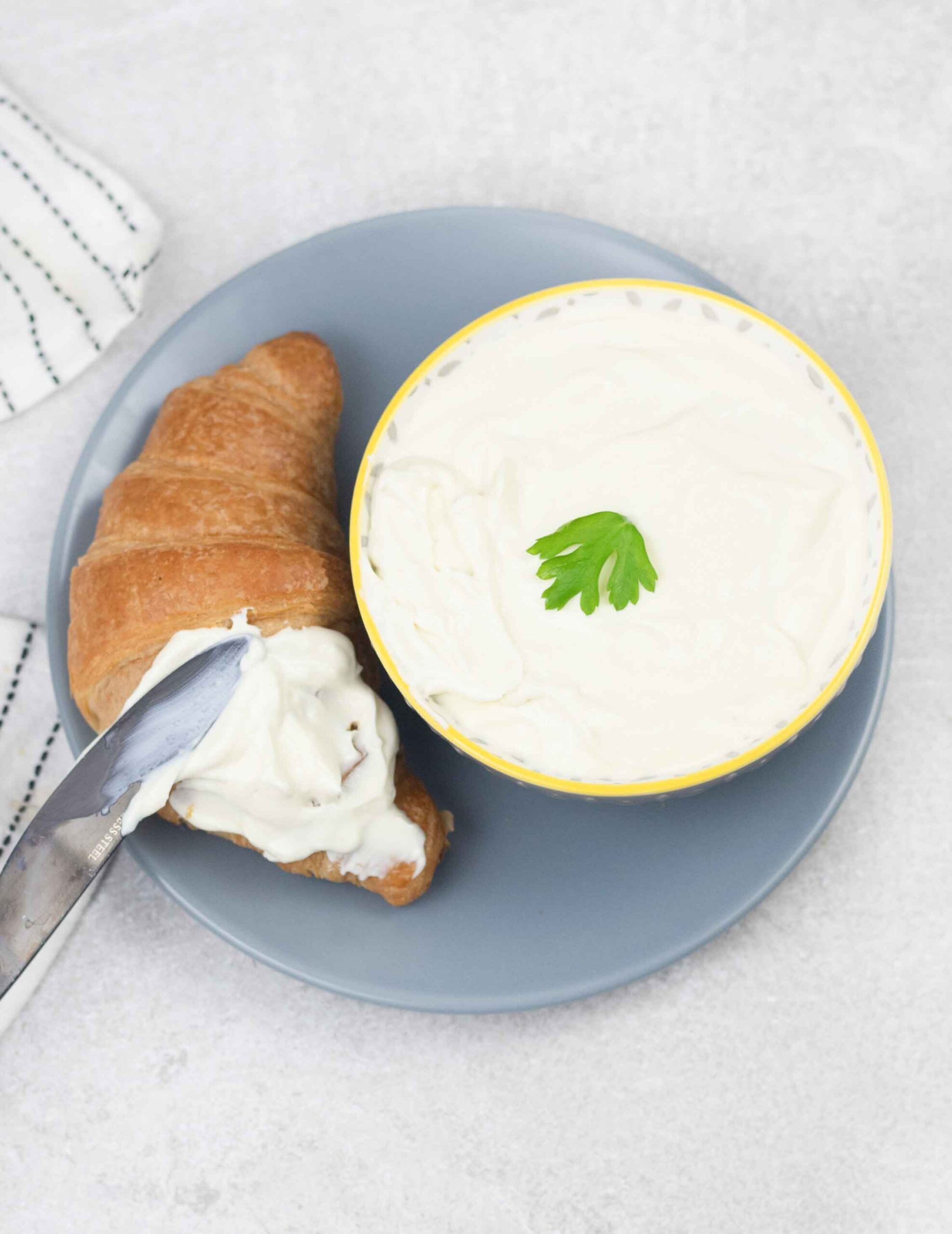 Spreading homemade cream cheese on croissant.