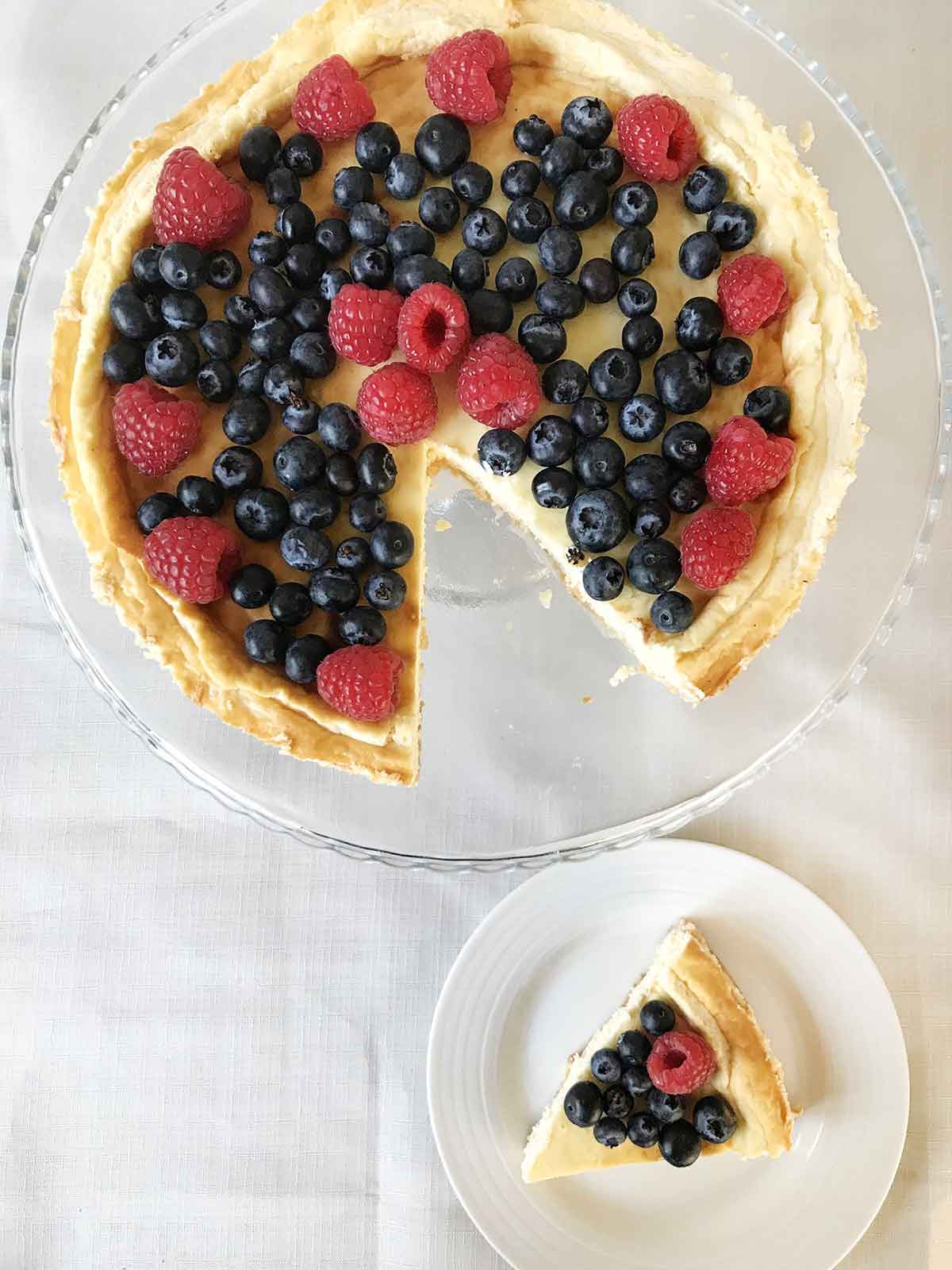 Philadelphia sugar free cheesecake slice in a plate and the whole cheesecake is on a stand.