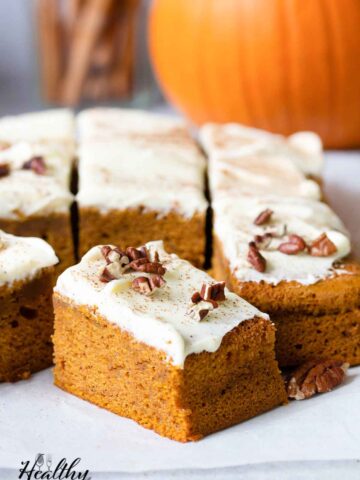 Pumpkin sheet cake with cream cheese frosting topped with chopped pecans.