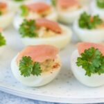 Smoked salmon deviled eggs topped with salmon and parsley.