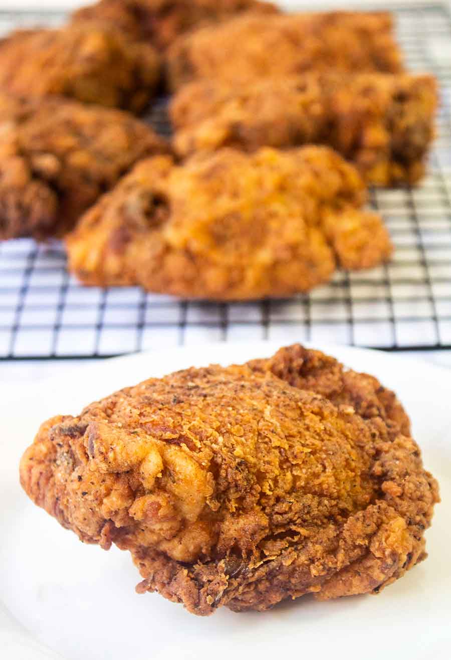 Fried chicken thighs on a wire rack.