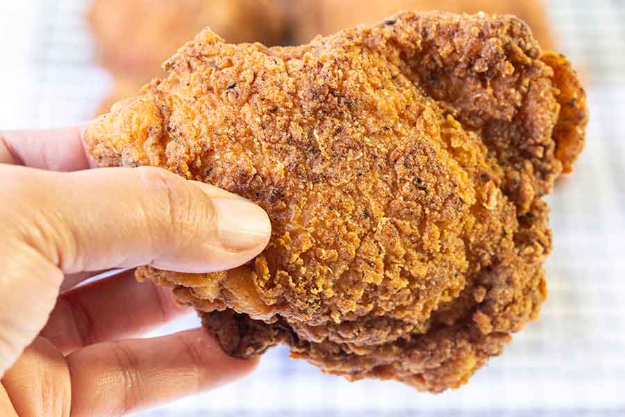 Holding one fried chicken thigh.