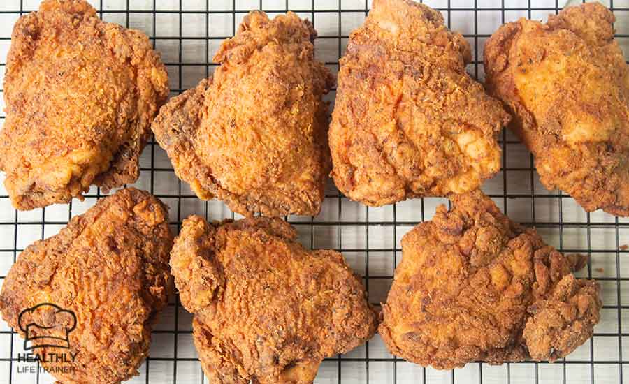 Fried chicken thighs on a wire rack.