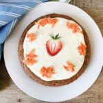 A whole gluten-free carrot cake made with almond flour and topped with shredded carrots.