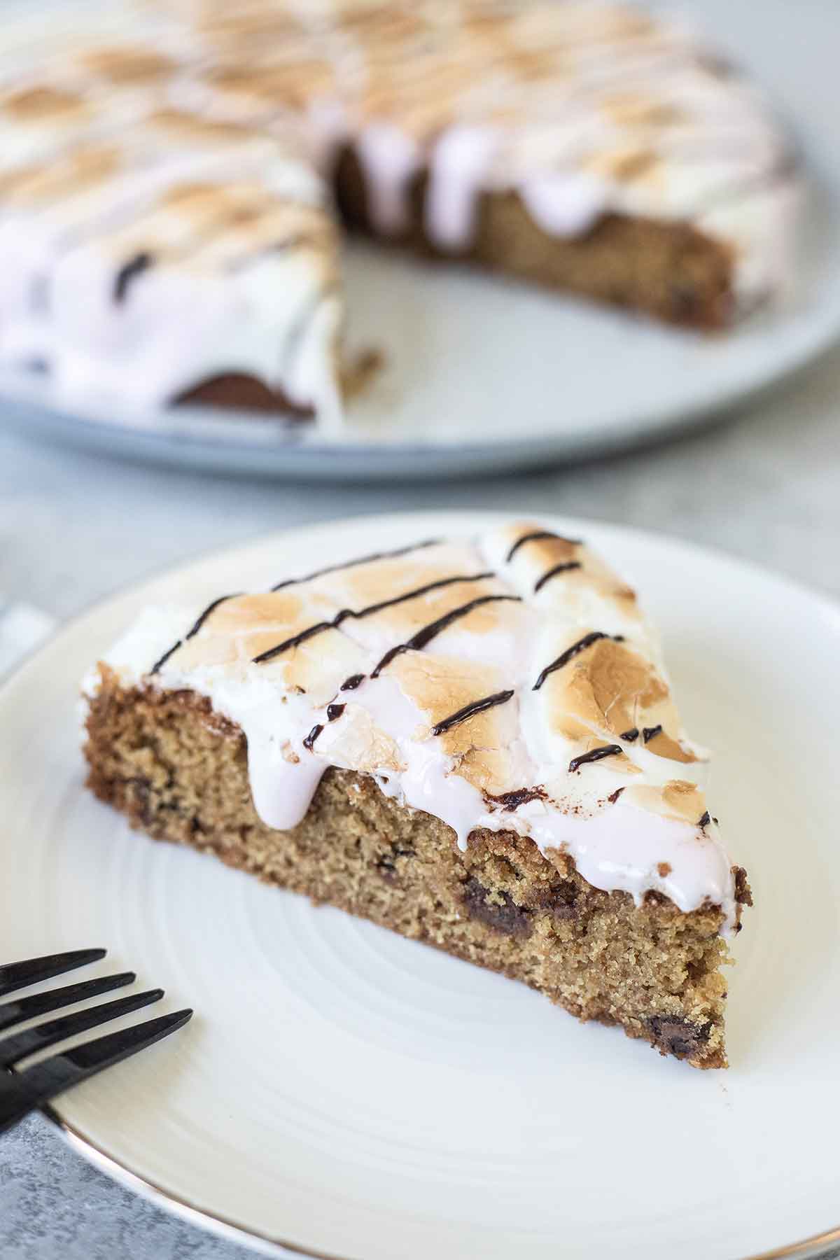 S'mores cookie cake slice topped with melted marshmallows on a plate.