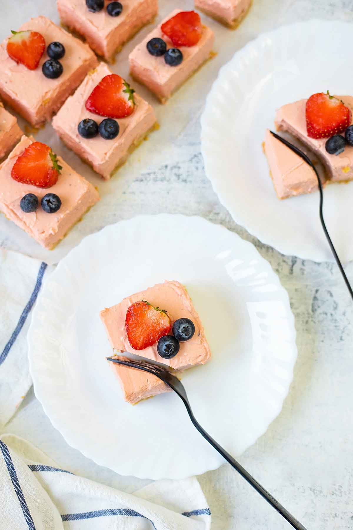 Cut a Philadelphia strawberry cheesecake bar with fork.