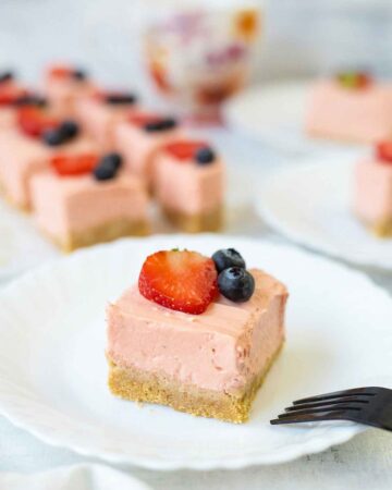 No baked Philadelphia strawberry cheesecake bars topped with berries.