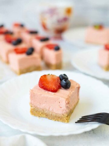 No baked Philadelphia strawberry cheesecake bars topped with berries.