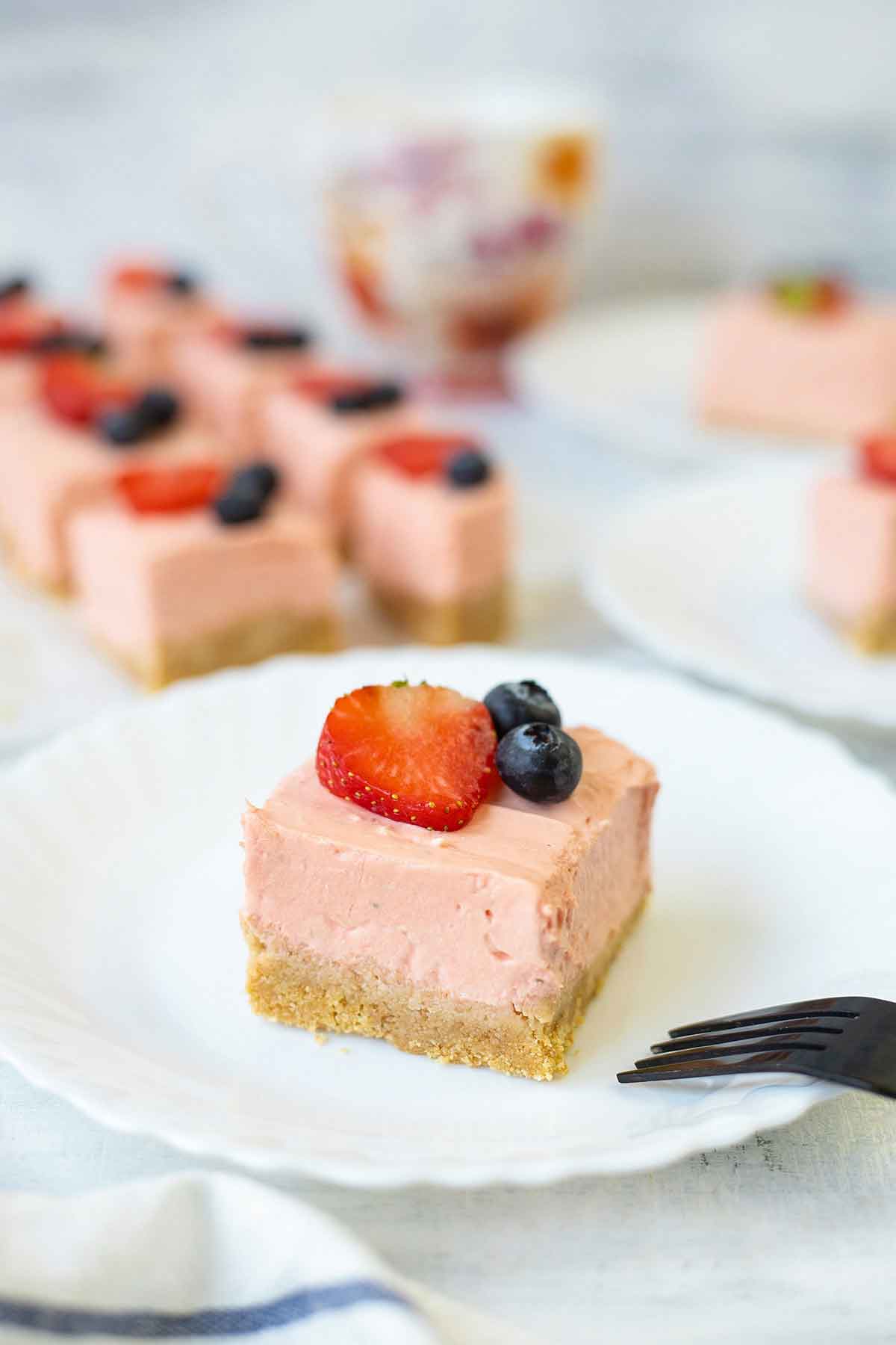 No baked Philadelphia strawberry cheesecake bars topped with berries.