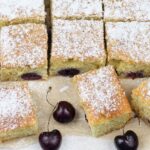 Slices of cherry cake and some fresh cherries are around.