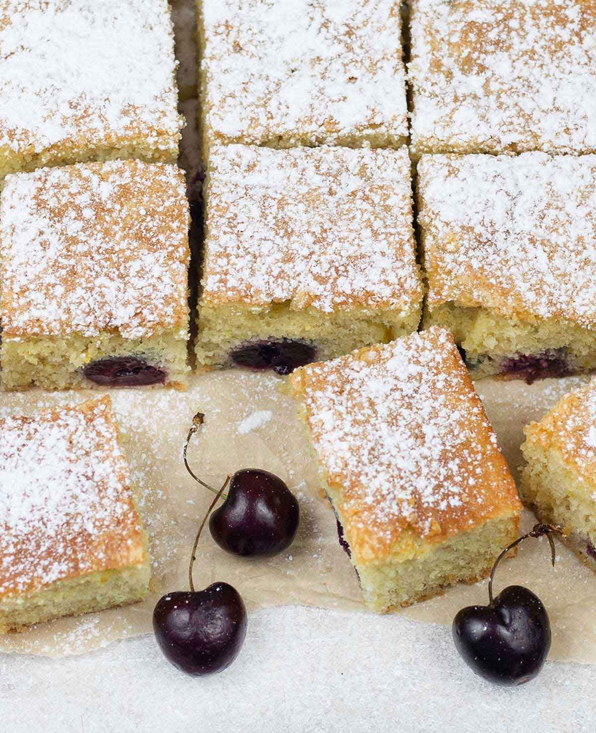 Slices of cherry cake and some fresh cherries are around.