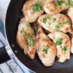 Garlic butter herb chicken breast in a large skillet topped with fresh herb.