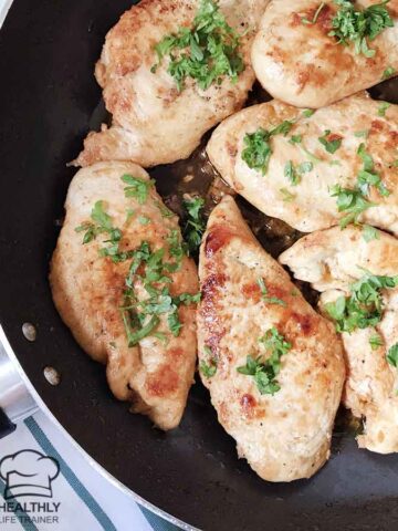 Garlic butter herb chicken breast in a large skillet topped with fresh herb.