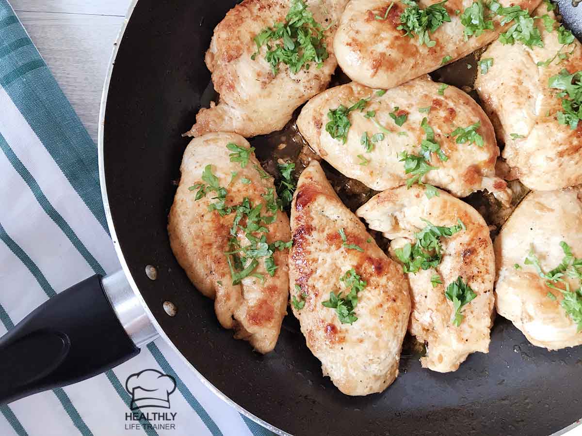 Garlic butter herb chicken breast in a large skillet topped with fresh herb.