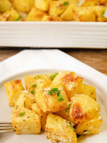 a plate with herb roasted potatoes garnished with fresh herbs.