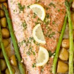 Salmon, asparagus and potatoes in a sheet pan topped with lemon slices.