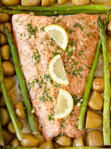 Salmon, asparagus and potatoes in a sheet pan topped with lemon slices.