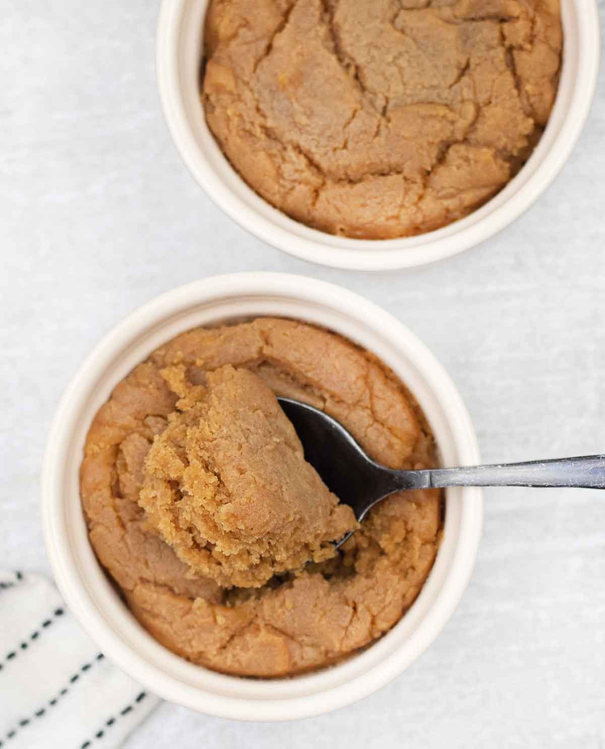 A spoonful of eggless peanut butter microwave cookies in a mug.