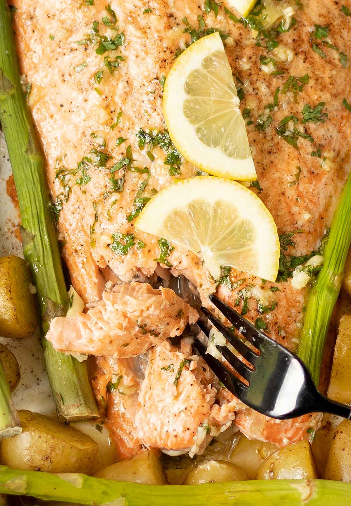 flake salmon with a fork, potatoes and asparagus.