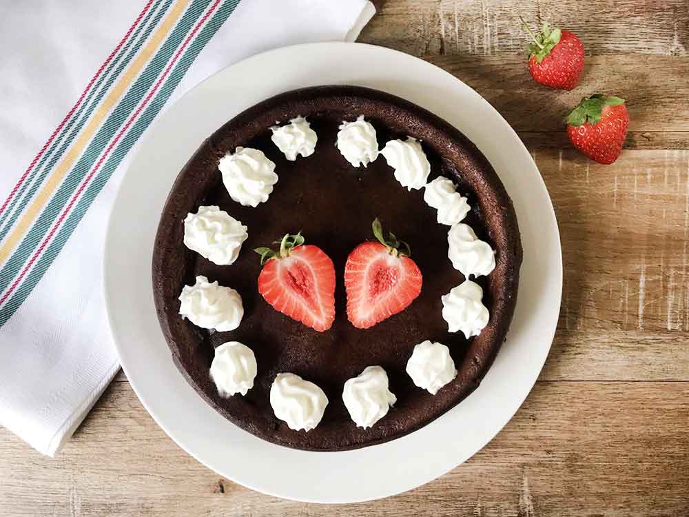 Keto flourless chocolate molten cake topped with whipped cream and fresh strawberry.