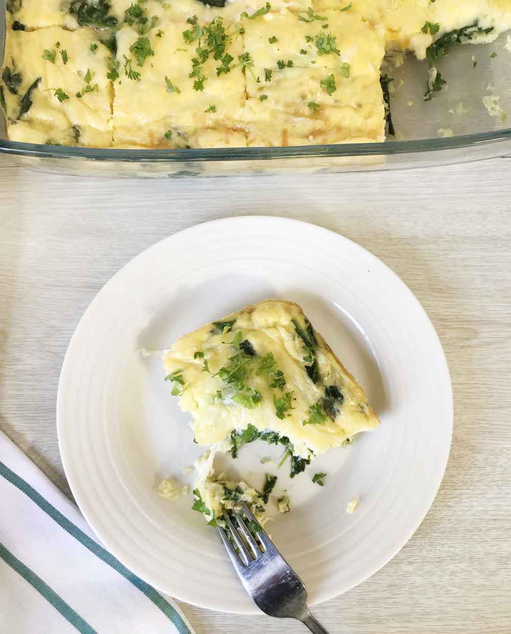 Cut a slice of the crustless spinach quiche with fork.