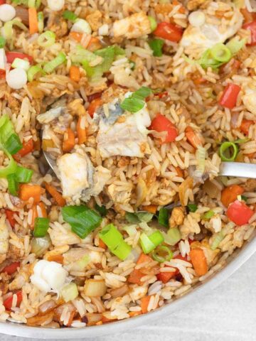 Scooping the fish rice with vegetables out of the pan.