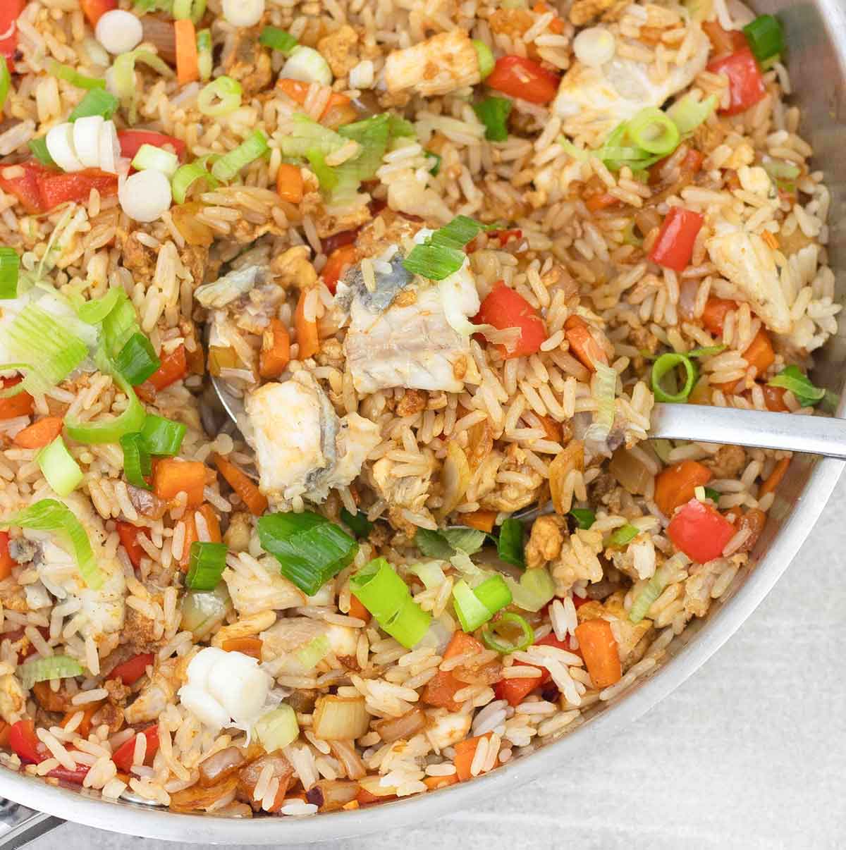 Scooping the fish rice with vegetables out of the pan.