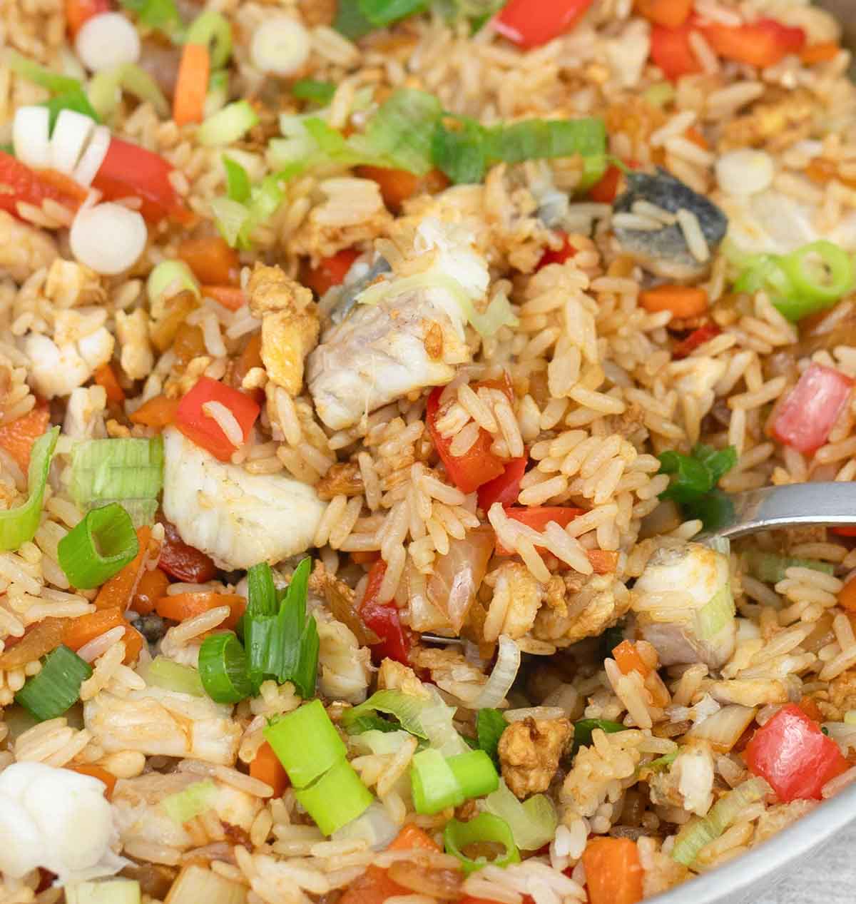 Fish rice with vegetables in a frying pan.