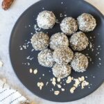 Date energy balls rolled in shredded coconut and a bowl of hazelnuts.