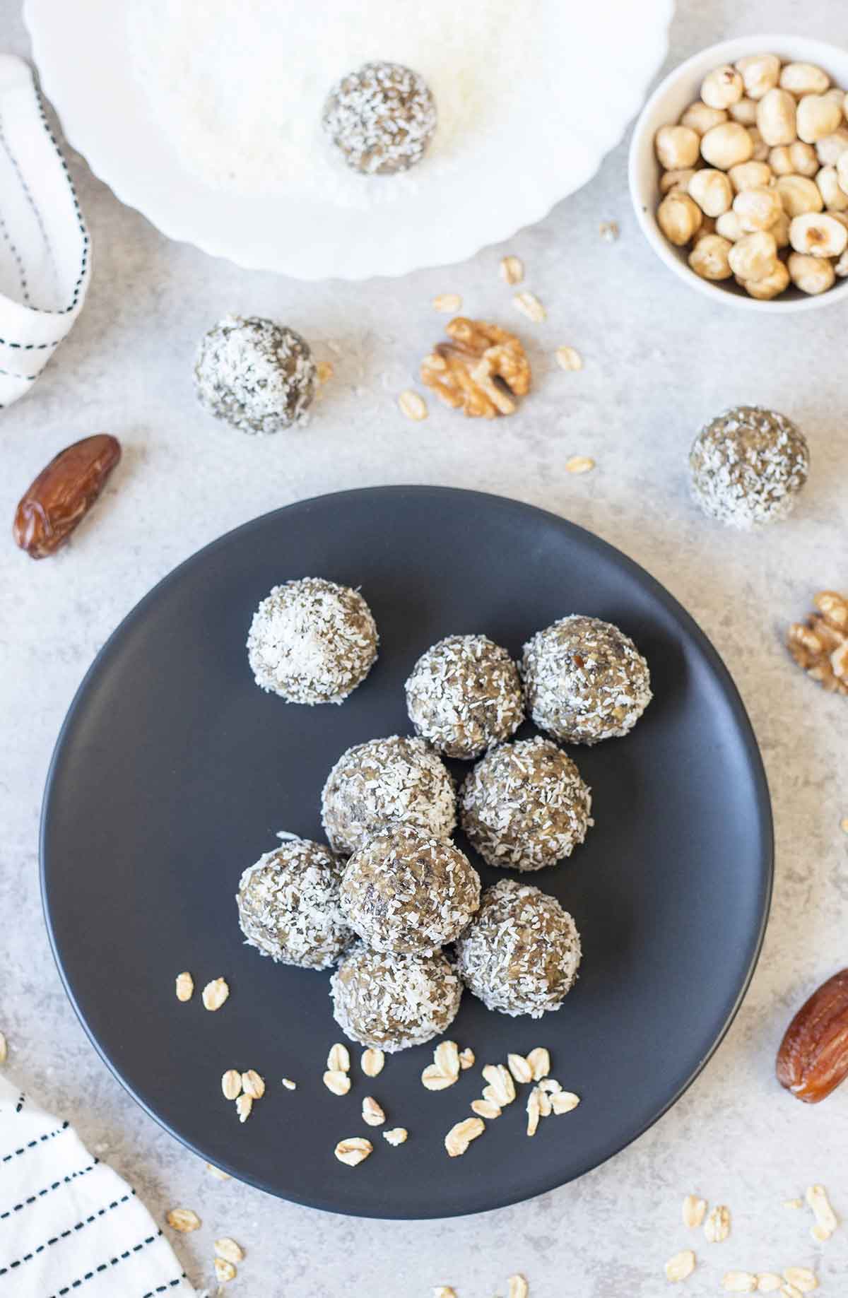 Date energy balls rolled in shredded coconut and a bowl of nuts and some dates.