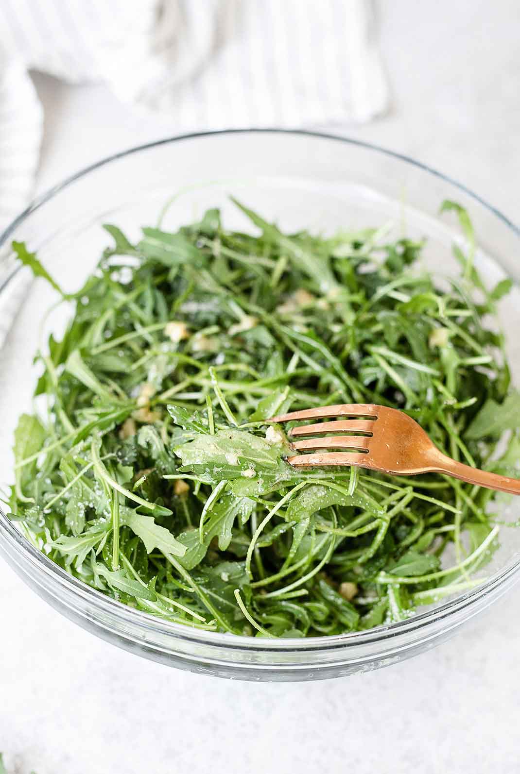 A forkful of rocket salad topped with simple vinaigrette dressing.