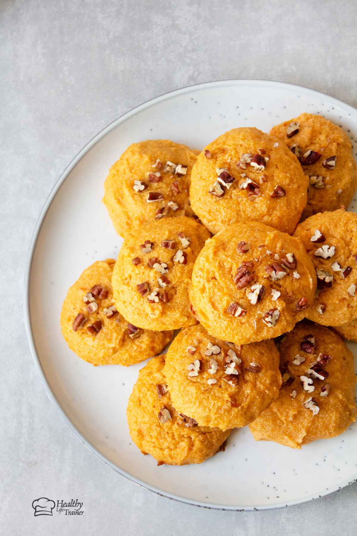 Sweet potato cookies in a serving plate topped with chopped pecan.