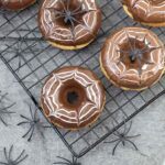 Halloween donuts decorated with spider web made from white and dark chocolate.