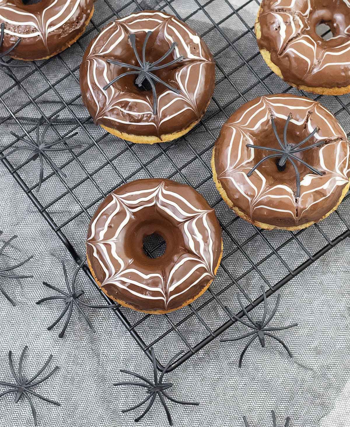 Halloween donuts decorated with spider web made from white and dark chocolate.