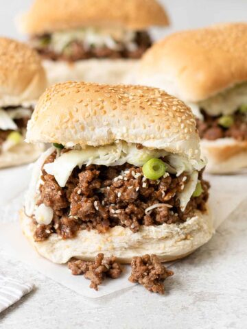 Asian sloppy joe sandwich topped with creamy slaw and green onion.