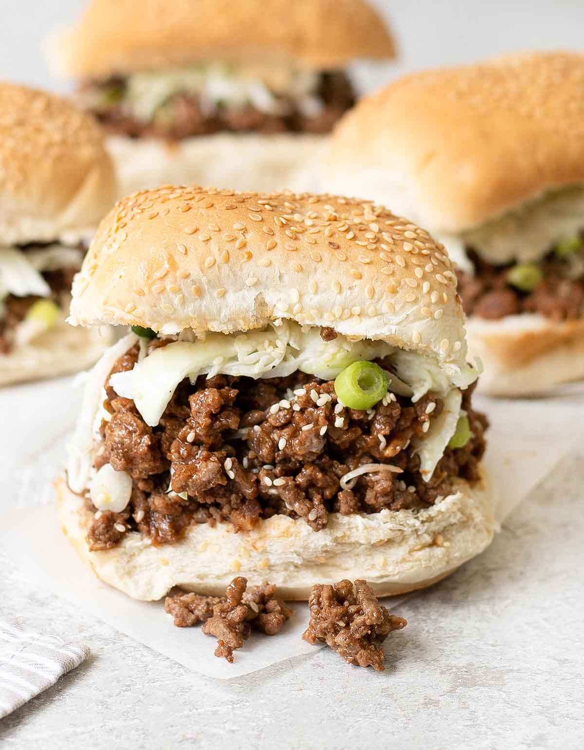 Asian sloppy joe sandwich topped with creamy slaw and green onion.