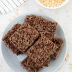 Chocolate rice krispie treats cut into squares and a small bowl of rice krispie.