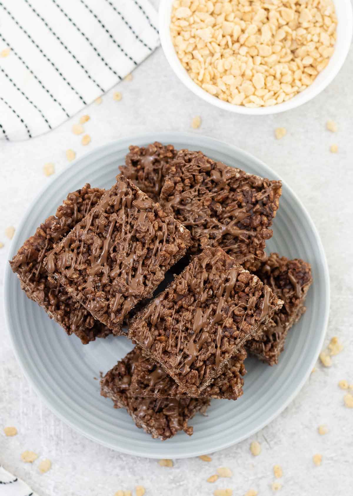 Chocolate rice krispie treats cut into squares and a small bowl of rice krispie.