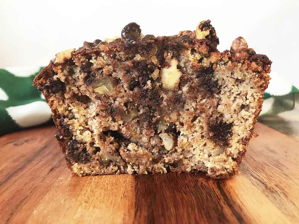 Keto banana bread cut into halves, showing chocolate chips and walnuts inside.