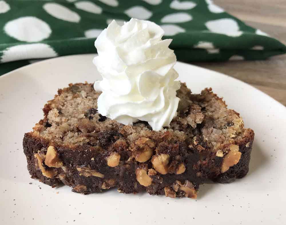 A slice of the keto banana walnut bread topped with whipped cream.