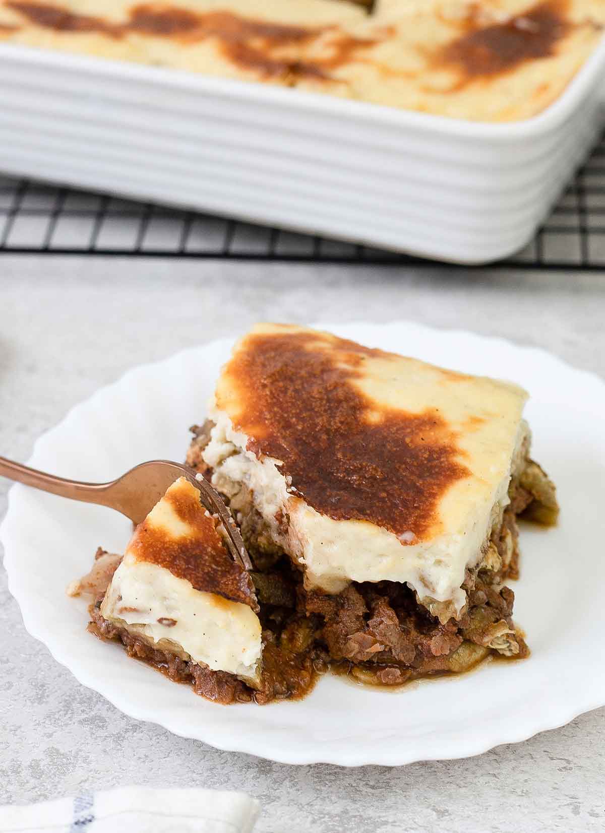 Eat a moussaka slice with fork.