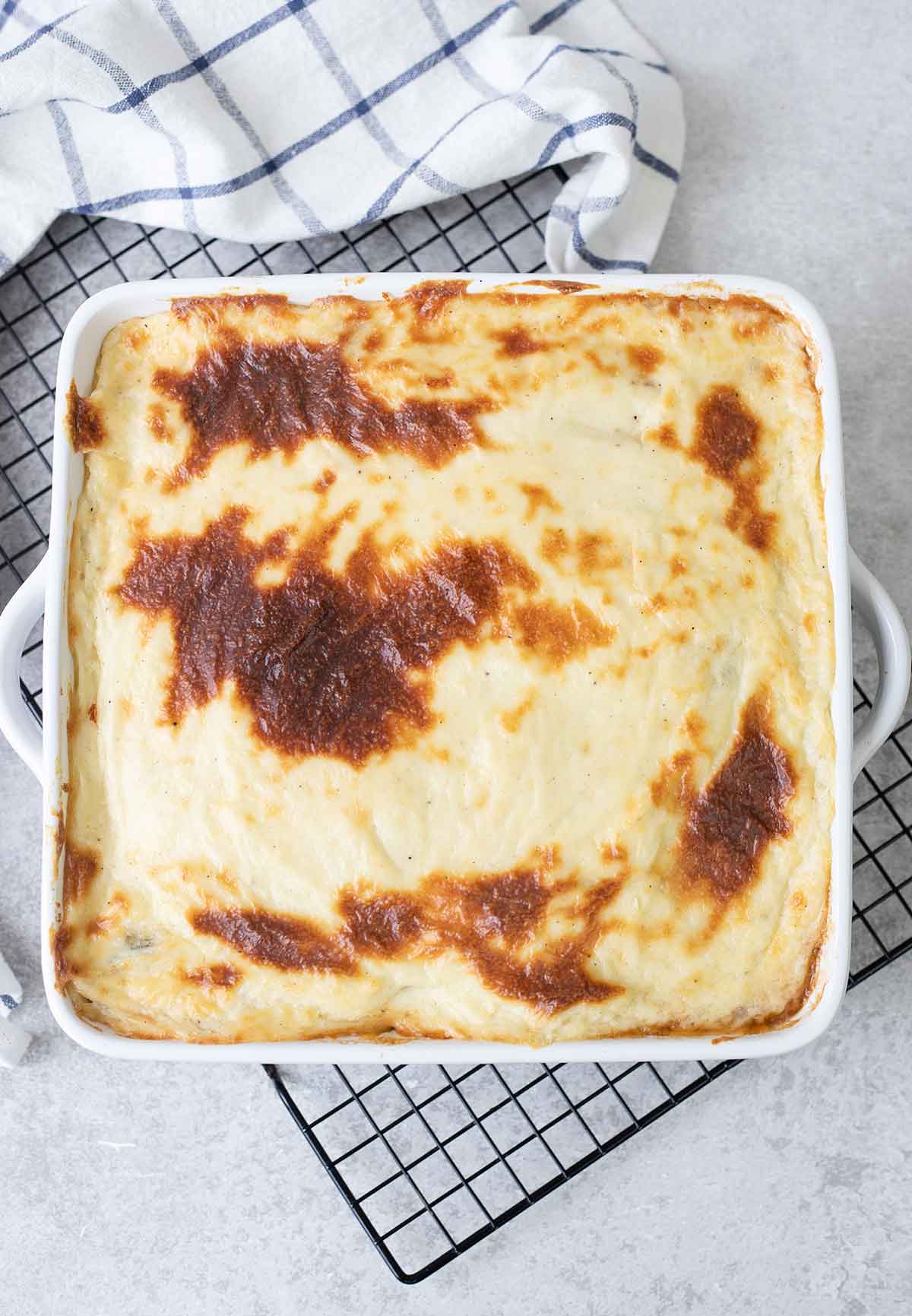 A whole baking dish full of Musaka after baking with a golden brown top.