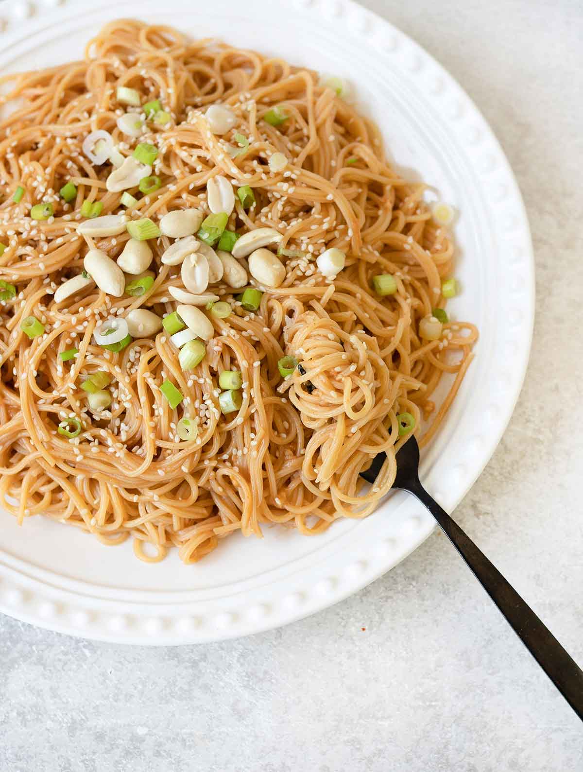 Eating the peanut butter and sesame noodles with fork.